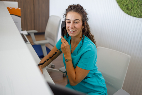 Smiling nurse answering phone call at reception desk stock photo
