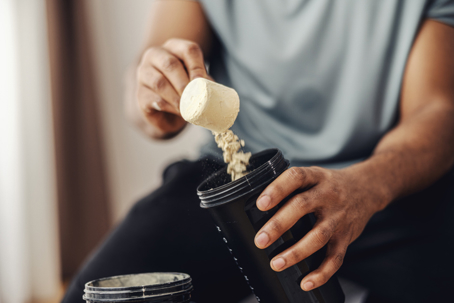 Person adding protein powder to shaker for fitness stock photo